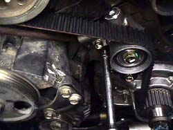 Using a prybar to push the auto tensioner in place
